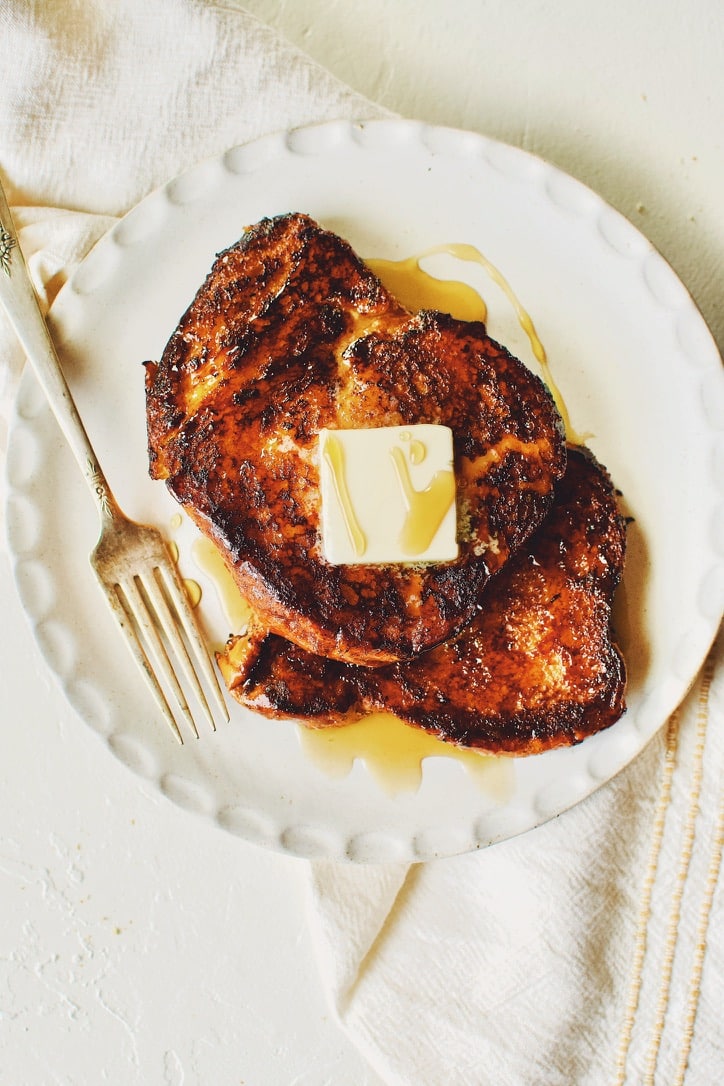 Finished French Toast sprinkled with cinnamon sugar, topped with butter, and drizzled with maple syrup.