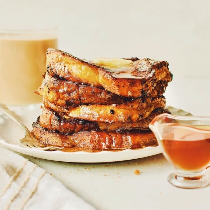 Finished French Toast sprinkled with cinnamon sugar, topped with butter, and drizzled with maple syrup.