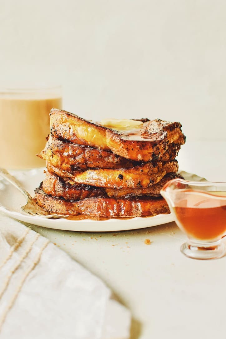 Finished French Toast sprinkled with cinnamon sugar, topped with butter, and drizzled with maple syrup.