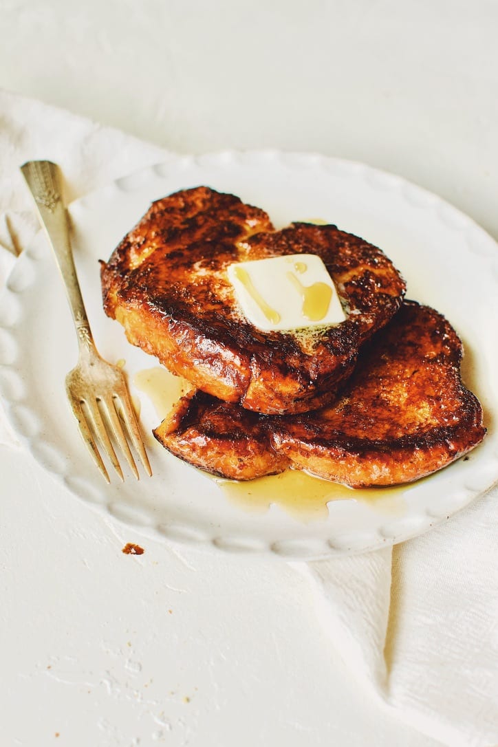 Finished French Toast sprinkled with cinnamon sugar, topped with butter, and drizzled with maple syrup.