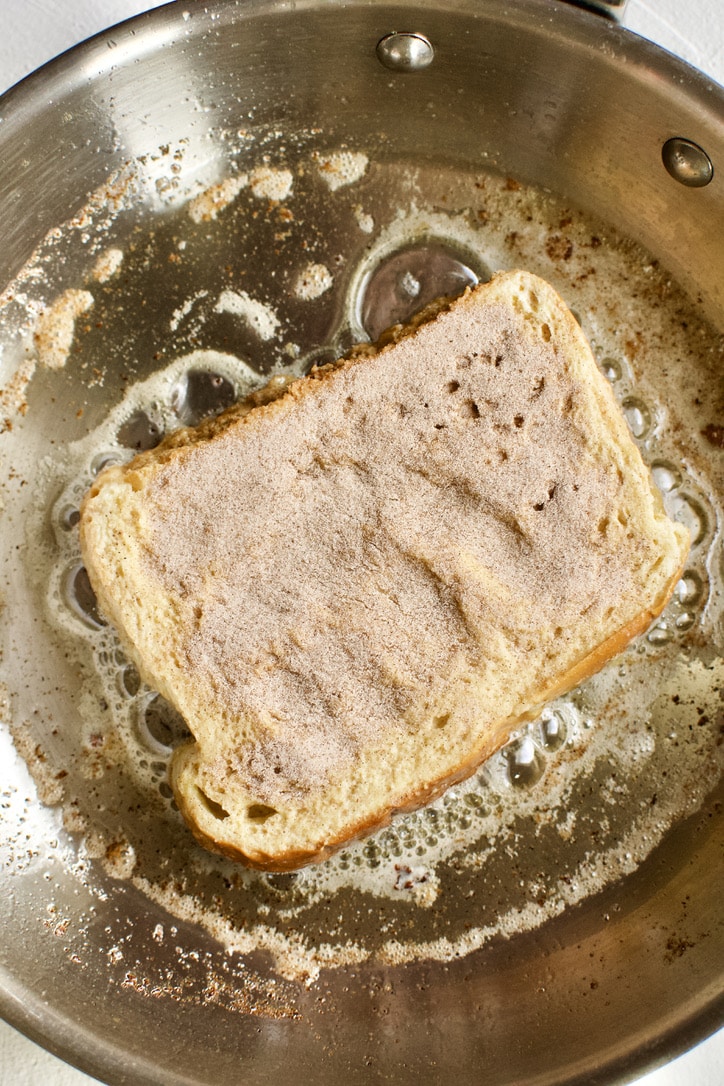 French Toast cooking on side one, side two dusted with cinnamon sugar.