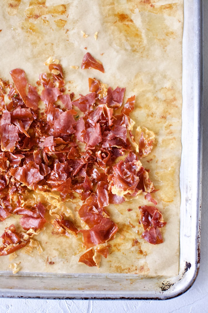 Crisp prosciutto on a parchment-lined baking sheet.