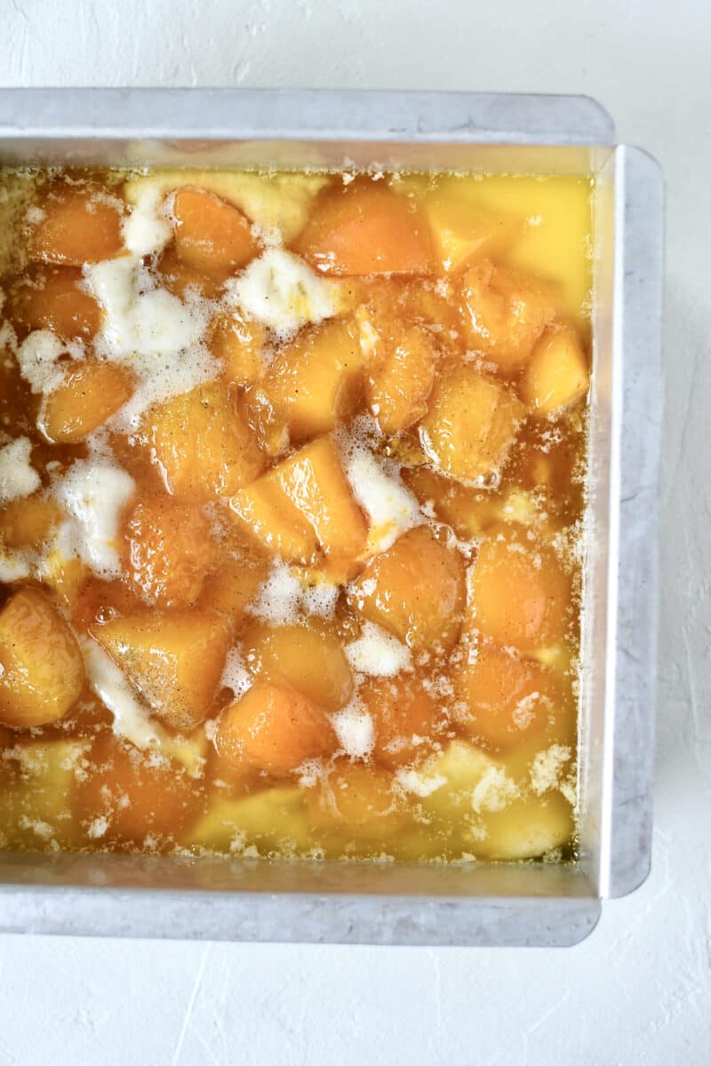 Apricots on top of batter in prepared baking tin.