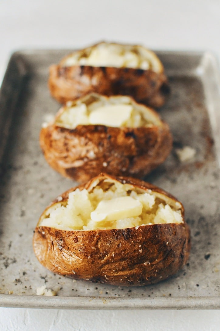 Crispy Skin Baked Potatoes fluffed and topped with butter.