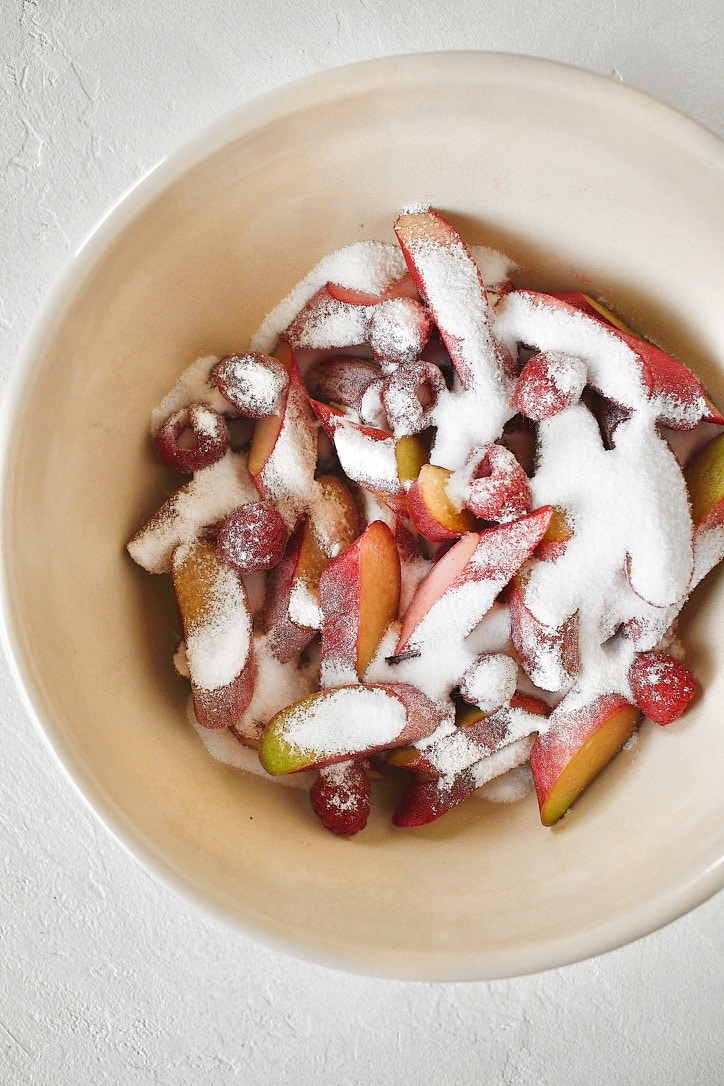 Rhubarb and Raspberries coated in sugar in a bowl.