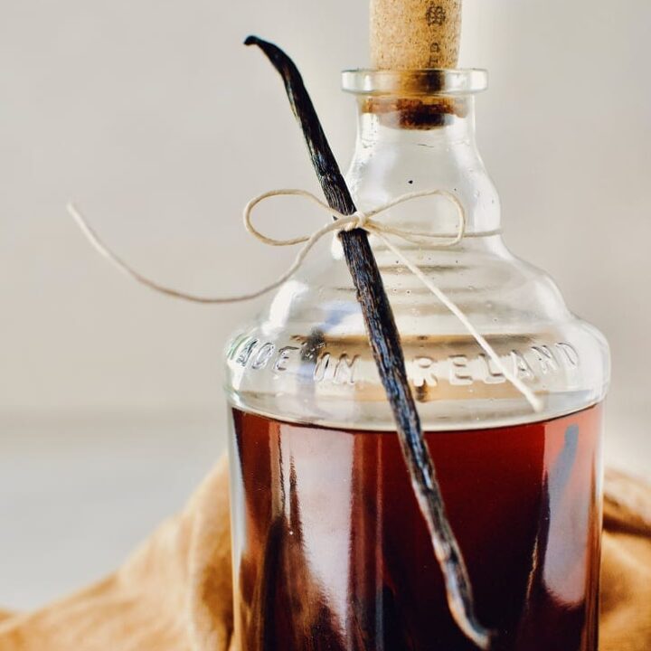 a bottle of aged vanilla extract, ready to be given as a gift, with a single vanilla bean tied to the neck.