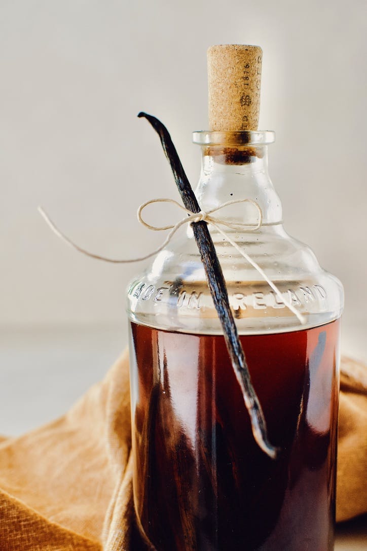 a bottle of aged vanilla extract, ready to be given as a gift, with a single vanilla bean tied to the neck.