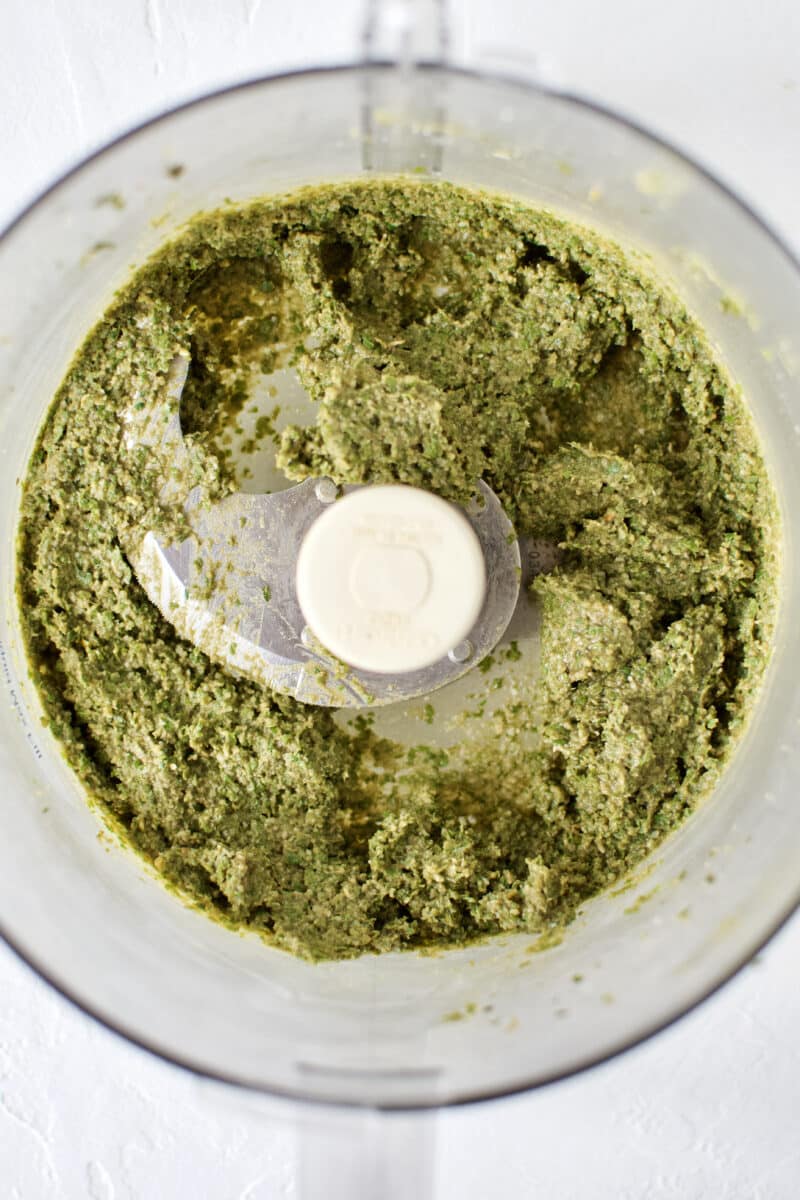 Fresh Basil Pesto, in the bottom of a food processor after adding the olive oil.