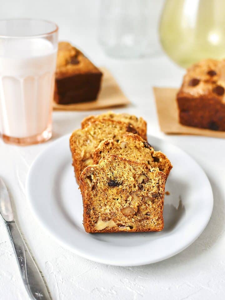 Slices of banana bread on a plate with a glass of milk nearby.