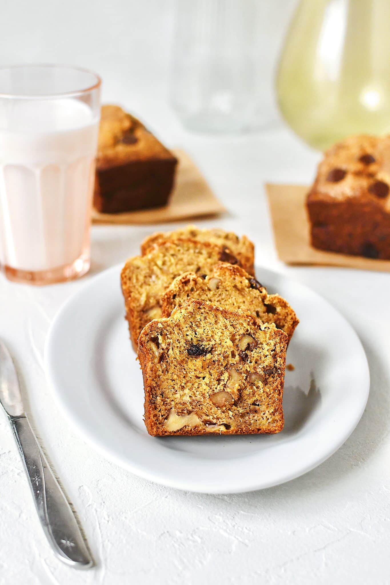 Slices of banana bread on a plate with a glass of milk nearby.