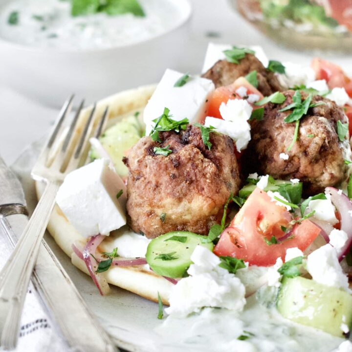 Greek Meatballs served with Greek Salad on top, over a pita bread with Tzatziki sauce.