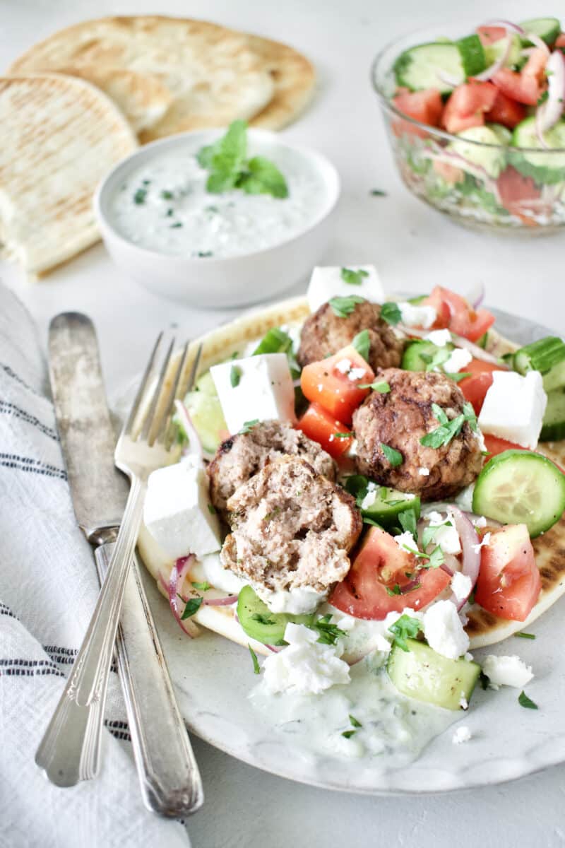 Greek Meatballs served with Greek Salad on top, over a pita bread with Tzatziki sauce.