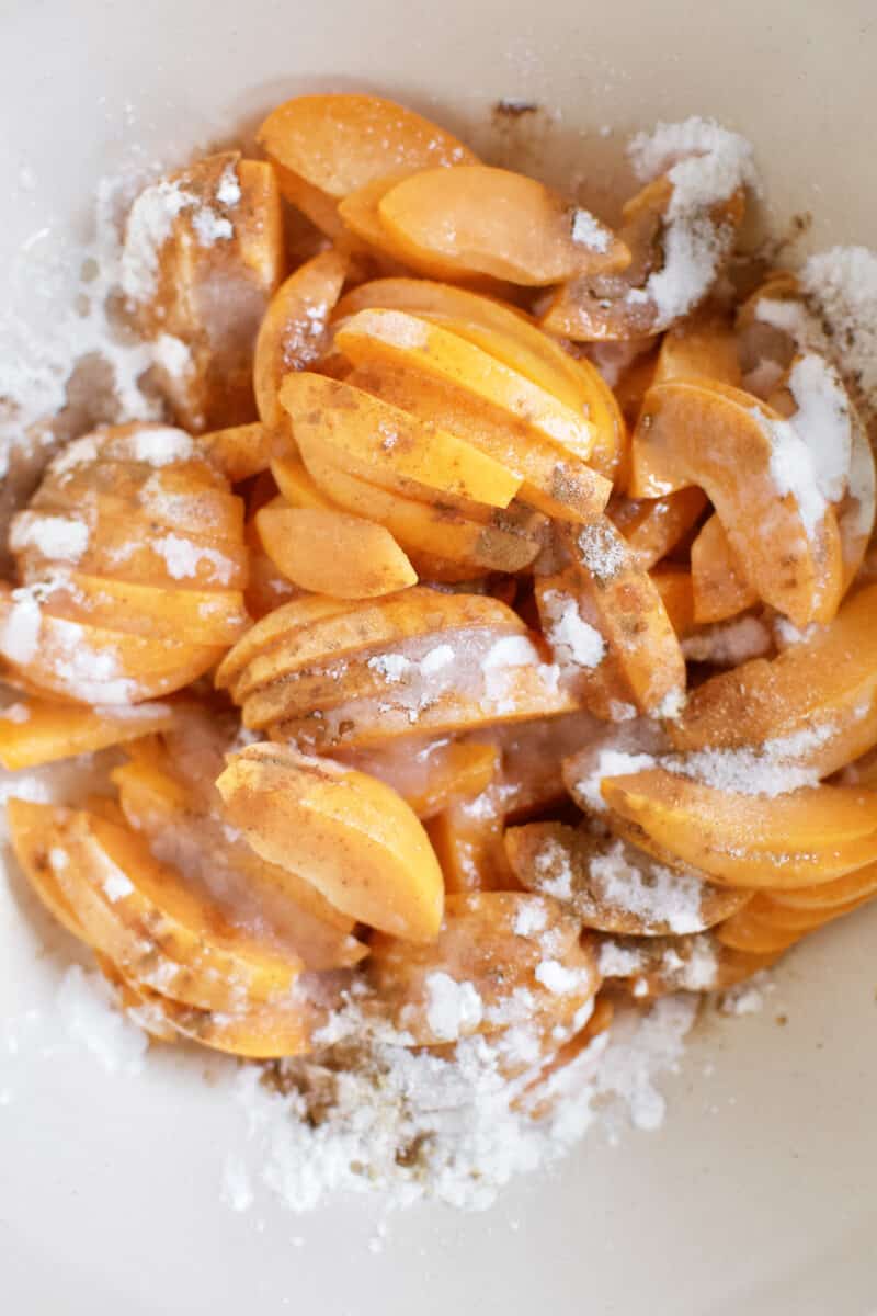 Fresh apricots sliced and placed in a large bowl, seasoned with spices, sugar, and cornstarch.
