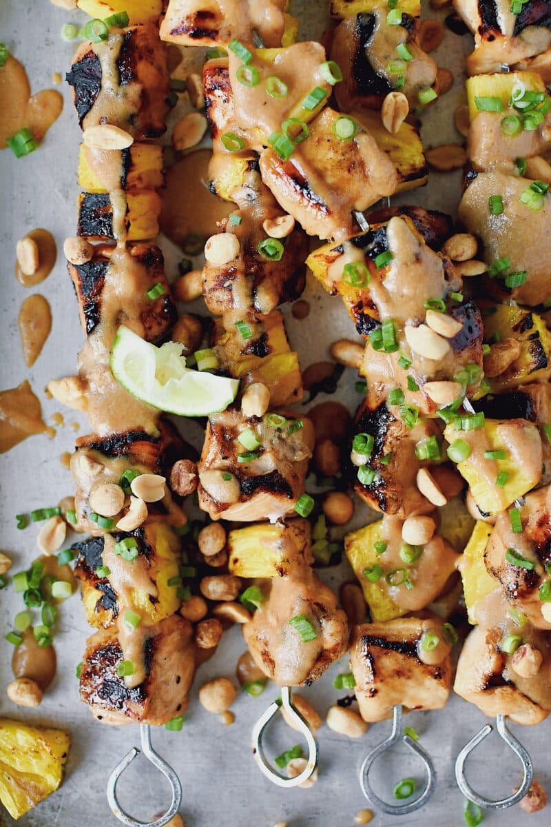 Pineapple Peanut Chicken Skewers fresh off the grill topped with peanut sauce, chopped green onions, and chopped peanuts.