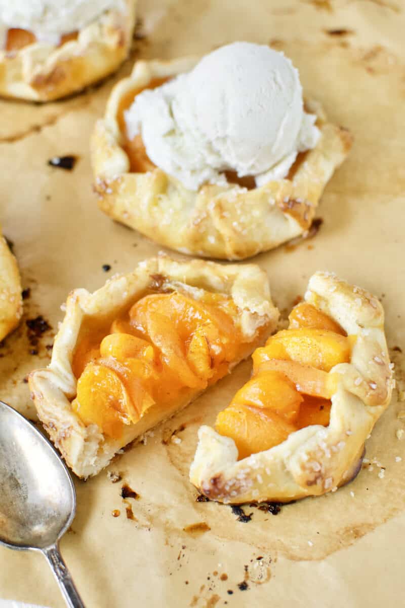 Apricot Pies fresh out of the oven, topped with vanilla ice cream. With one pie sliced open in the foreground.