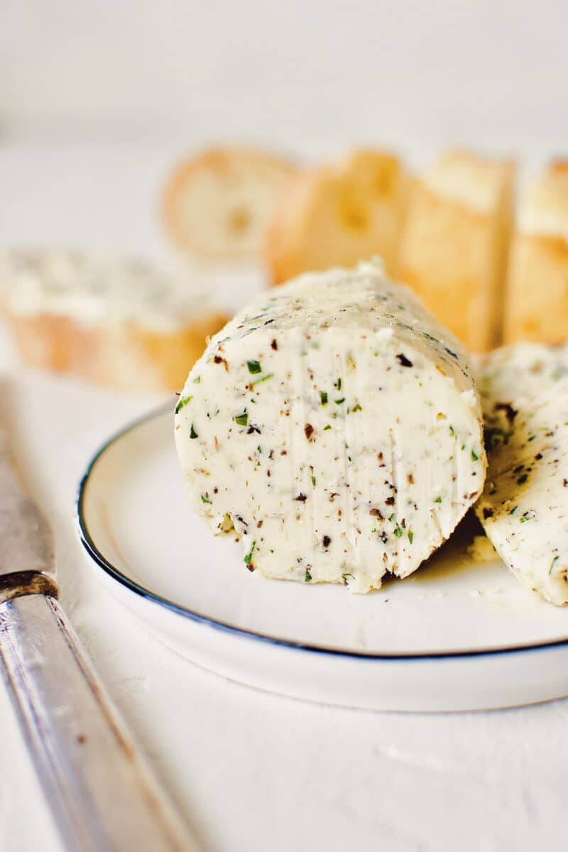 Black Truffle Butter log, on a plate with a knife and a couple slices on the plate.