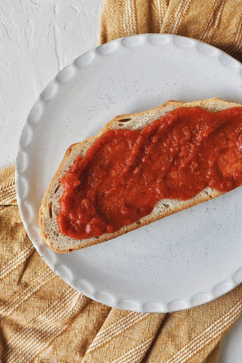 Building a Parmesan Chicken Sandwich, toasted bread with marinara sauce on top.