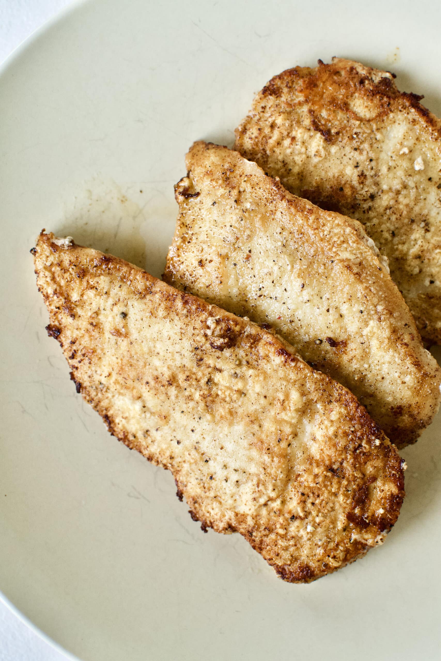 Seasoned chicken that has been browned in butter and olive oil in a hot pan.