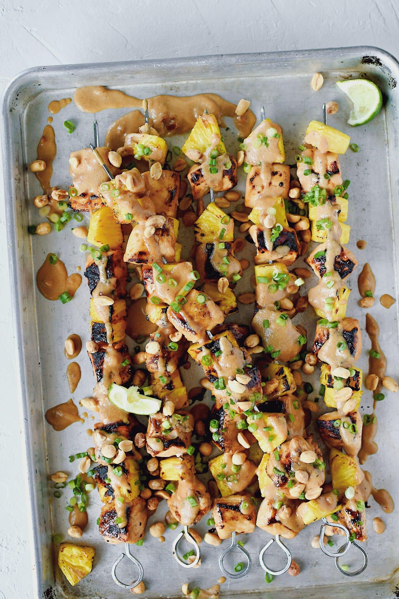 Pineapple Peanut Chicken Skewers fresh off the grill topped with peanut sauce, chopped green onions, and chopped peanuts.