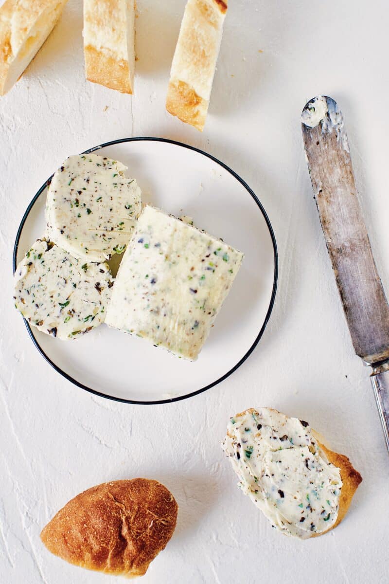 Black Truffle Butter log, on a plate with a knife and a couple slices on the plate.