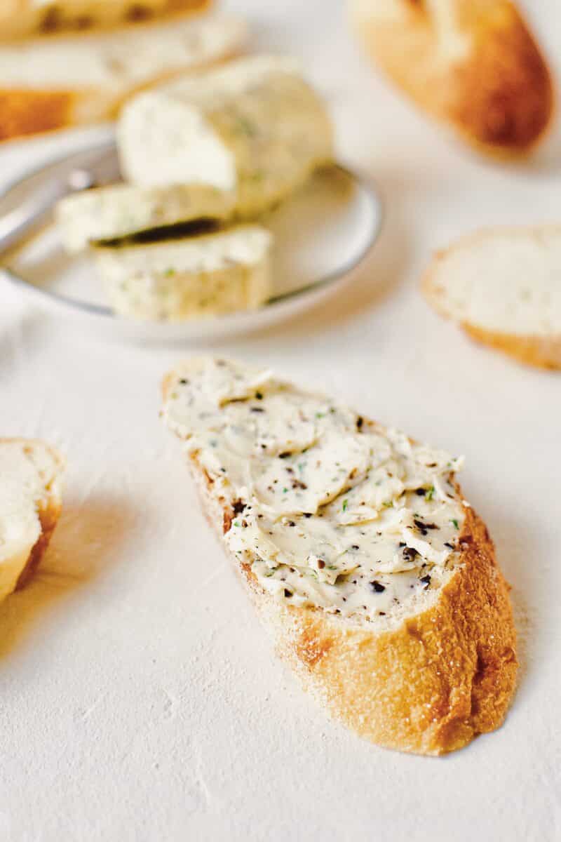 Black Truffle Butter log, on a plate with a knife and a couple slices on the plate.