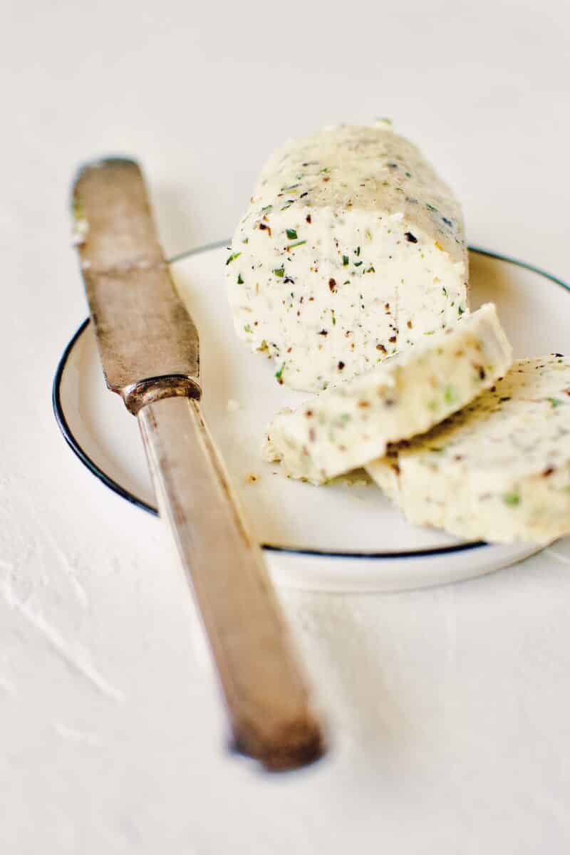 Black Truffle Butter log, on a plate with a knife and a couple slices on the plate.