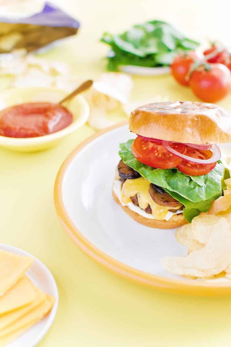 Not-So "Basic" Burger stacked up on a plate with chips and my favorite toppings.