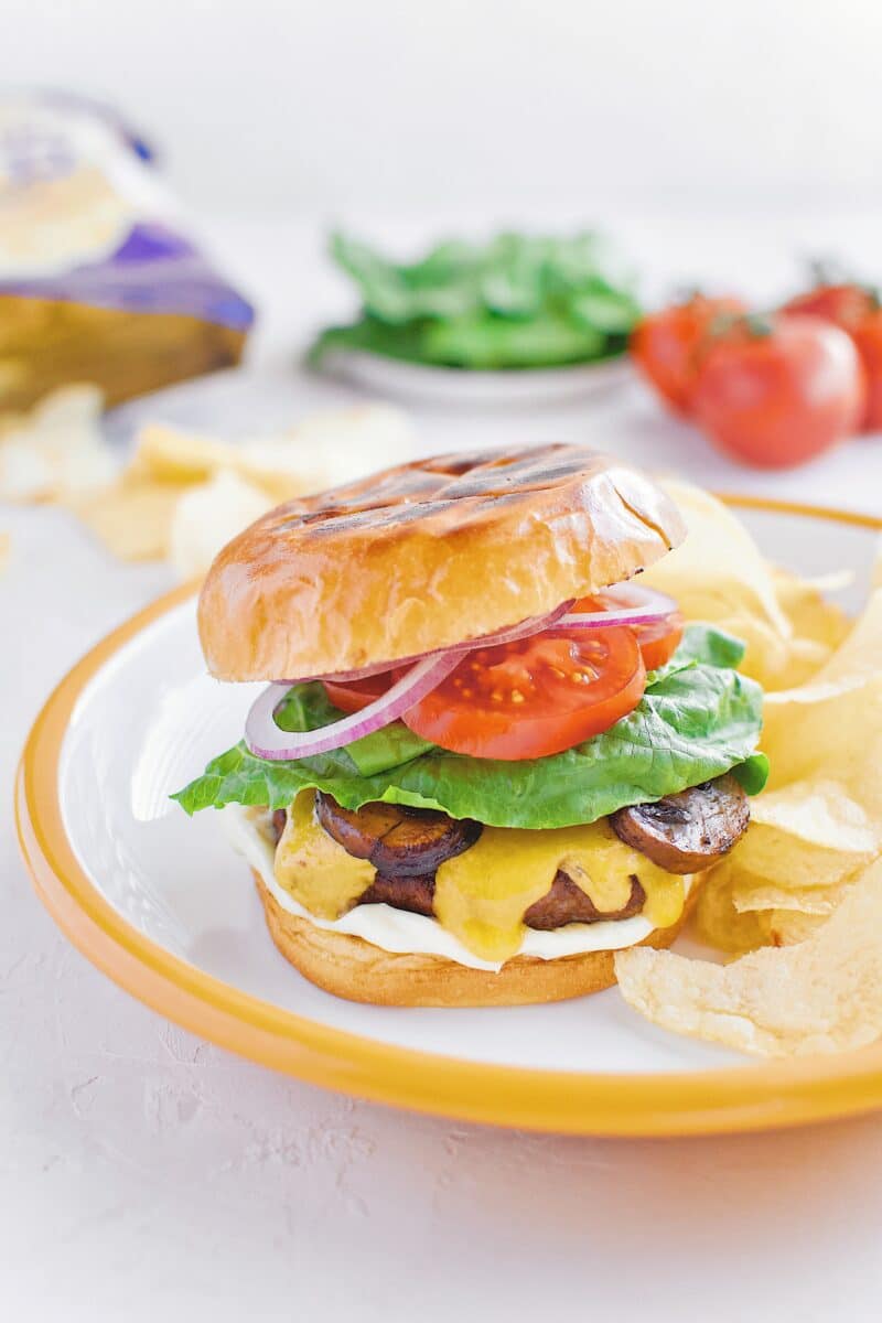 Not-So "Basic" Burger stacked up on a plate with chips and my favorite toppings.