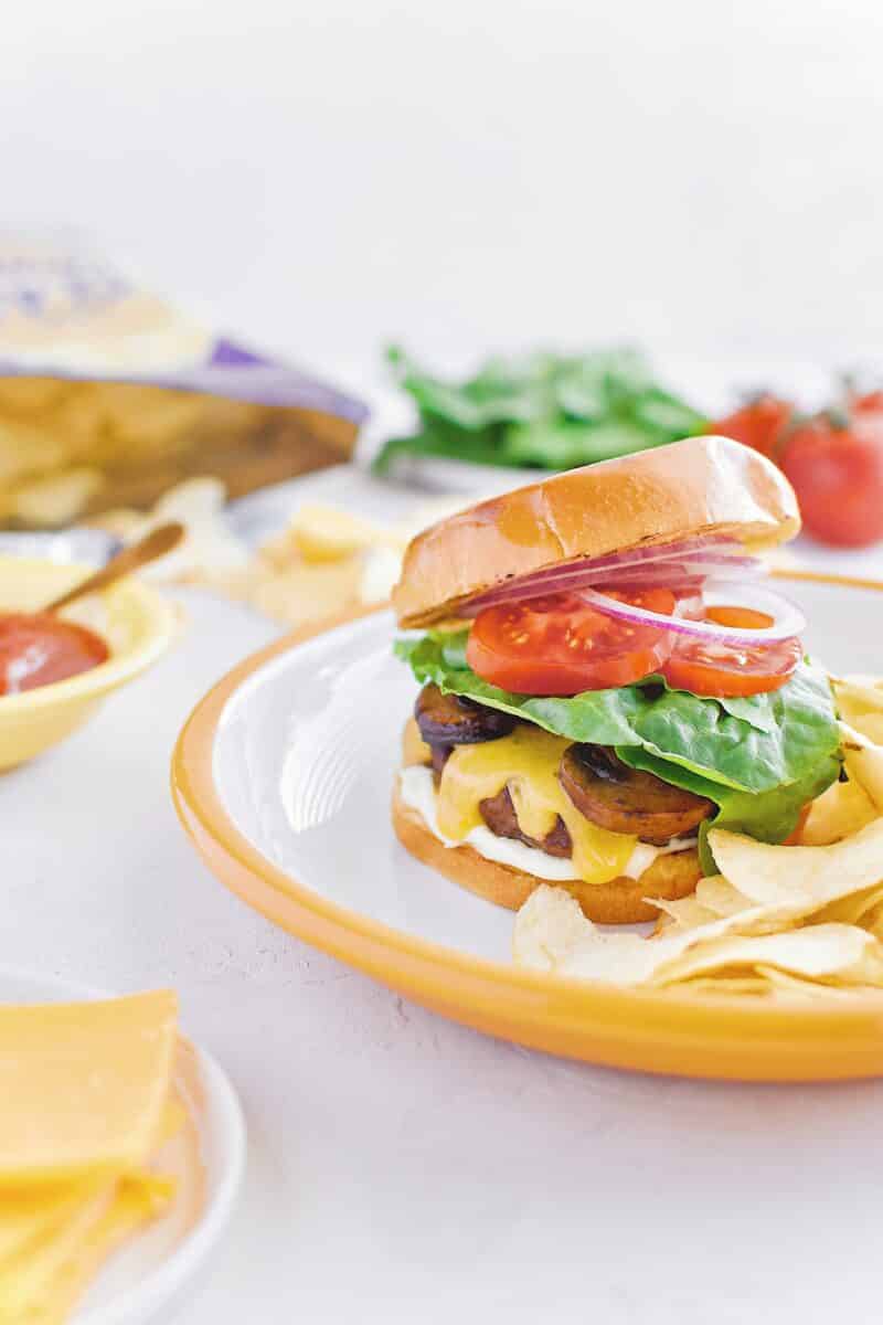 Not-So "Basic" Burger stacked up on a plate with chips and my favorite toppings.