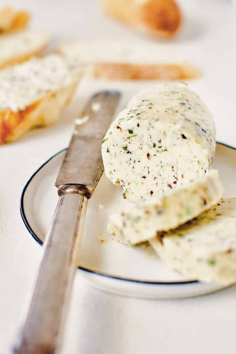 Black Truffle Butter log, on a plate with a knife and a couple slices on the plate.