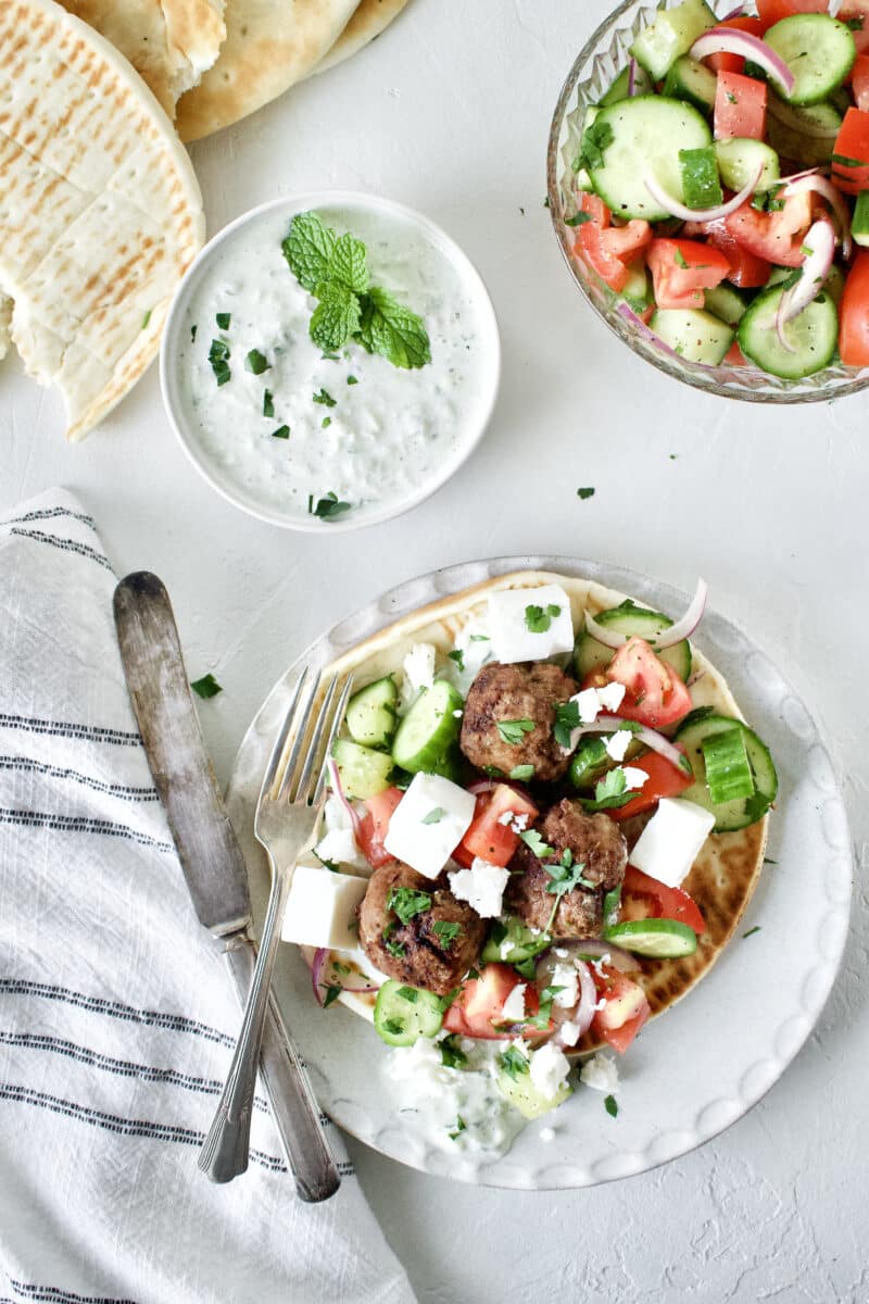 Greek Meatballs served with Greek Salad on top, over a pita bread with Tzatziki sauce.