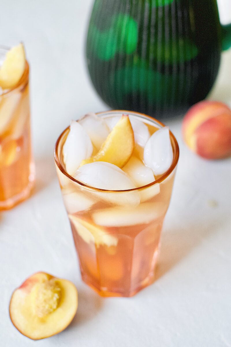 Peach Sangria in an ice filled glass with peach wedges.