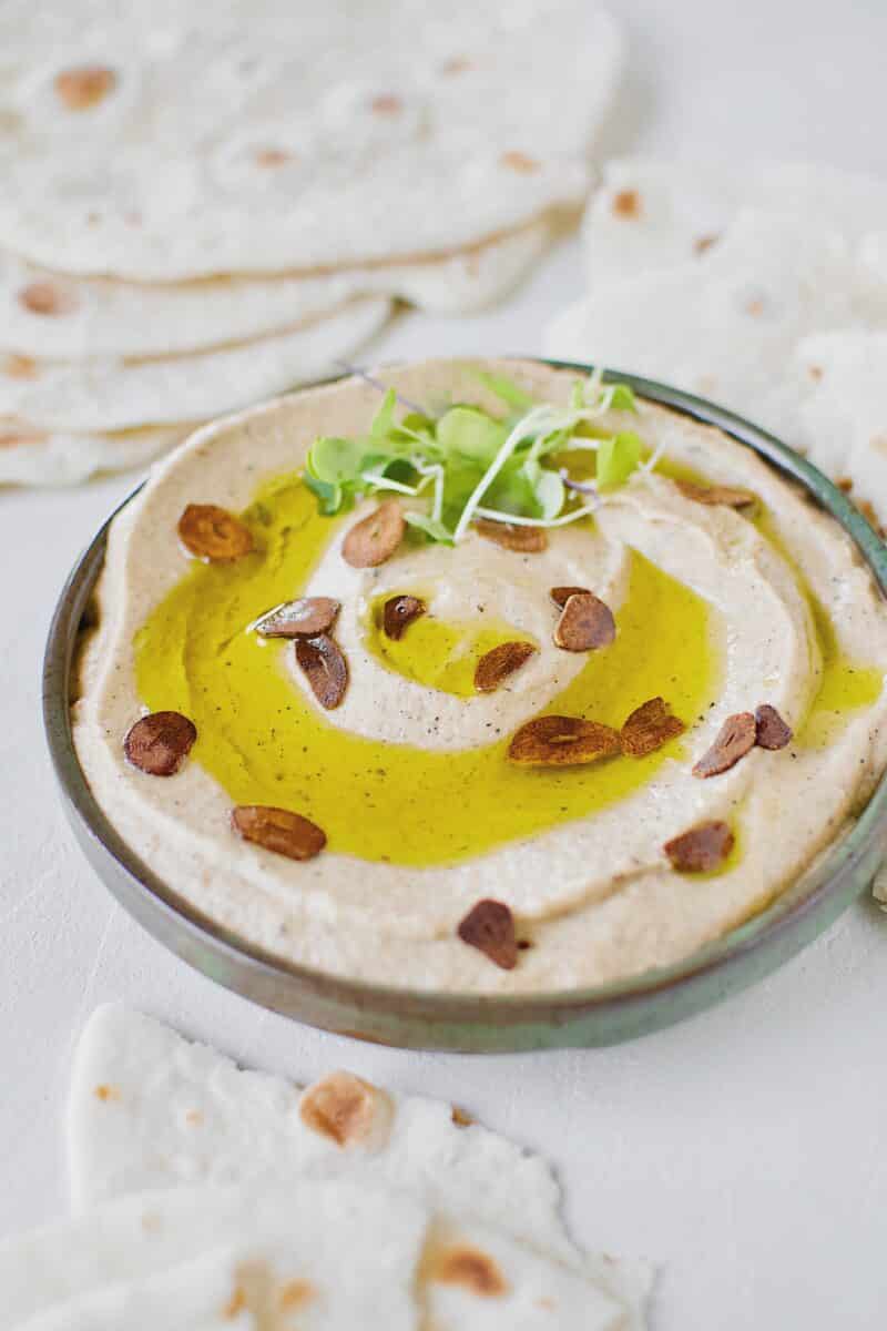 Baba Ghanoush with Toasted Garlic in a bowl, topped with olive oil and sliced toasted garlic.