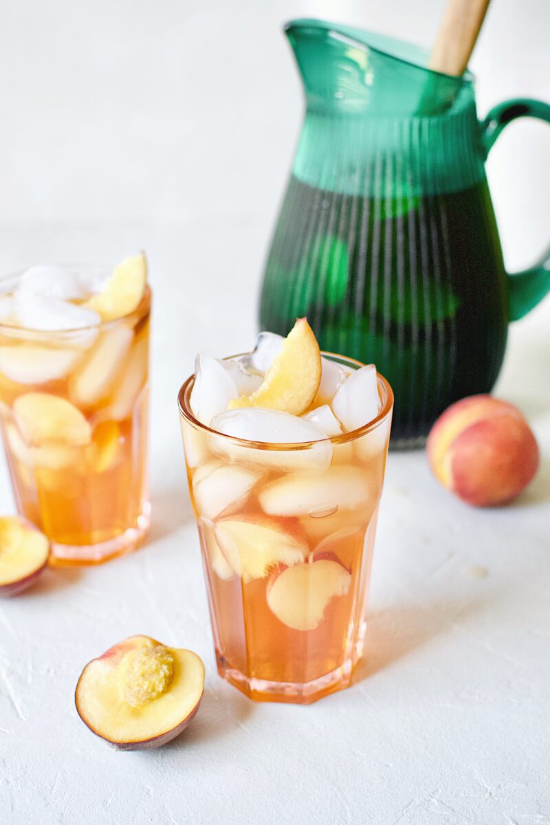 Peach Sangria in an ice filled glass with peach wedges.