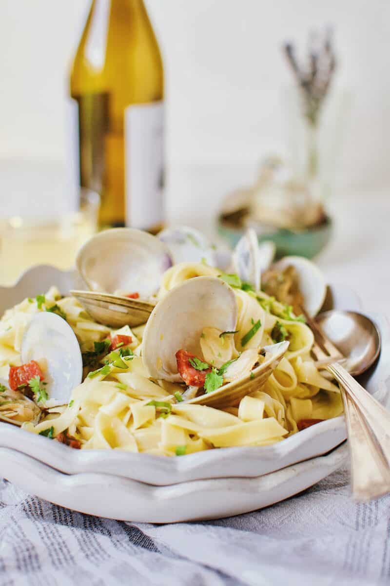 Linguine with Clam Sauce served in a bowl with a glass of white wine in the background.