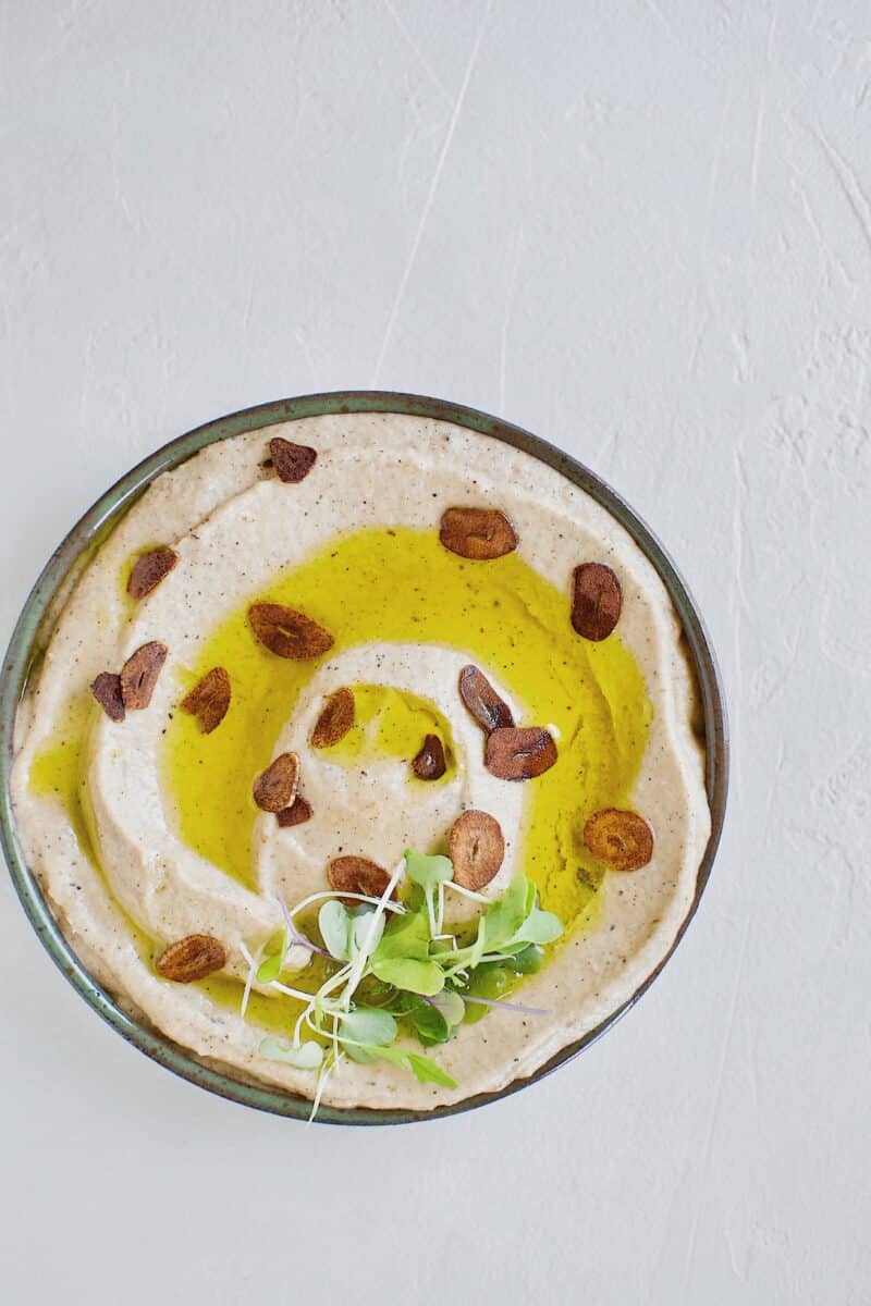 Baba Ghanoush with Toasted Garlic in a bowl, topped with olive oil and sliced toasted garlic.