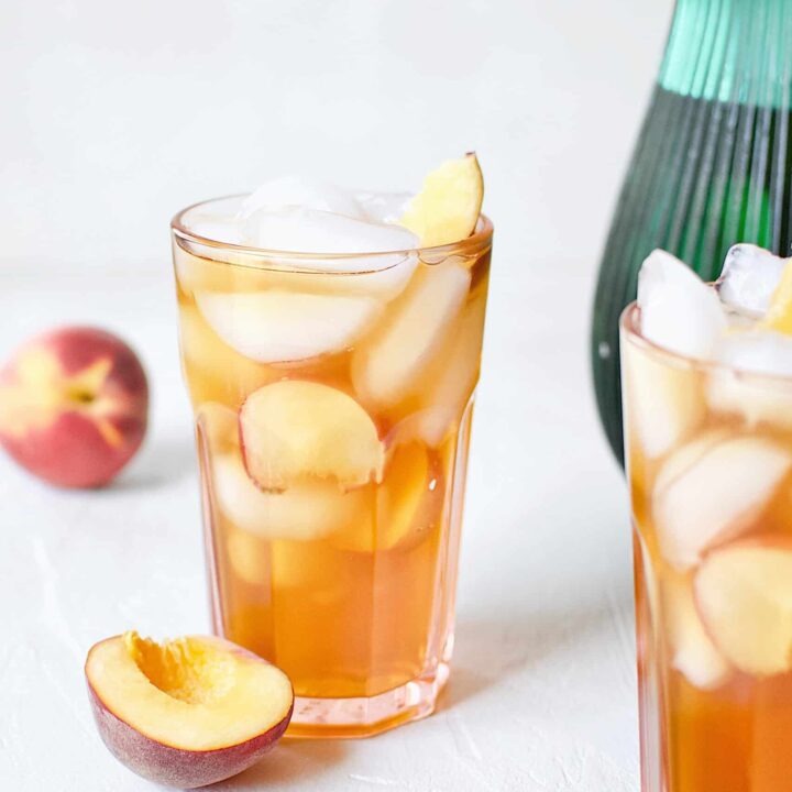 Peach Sangria in an ice-filled glass with peach wedges.