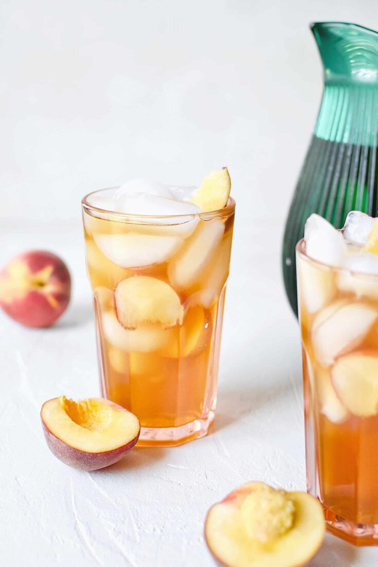 Peach Sangria in an ice-filled glass with peach wedges.