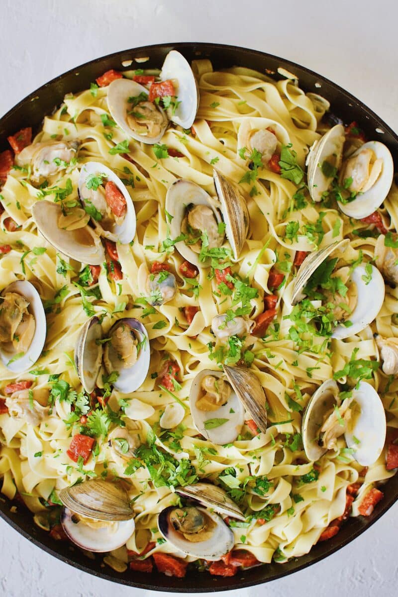 Pasta tossed with all ingredients, and served with clams added on top.