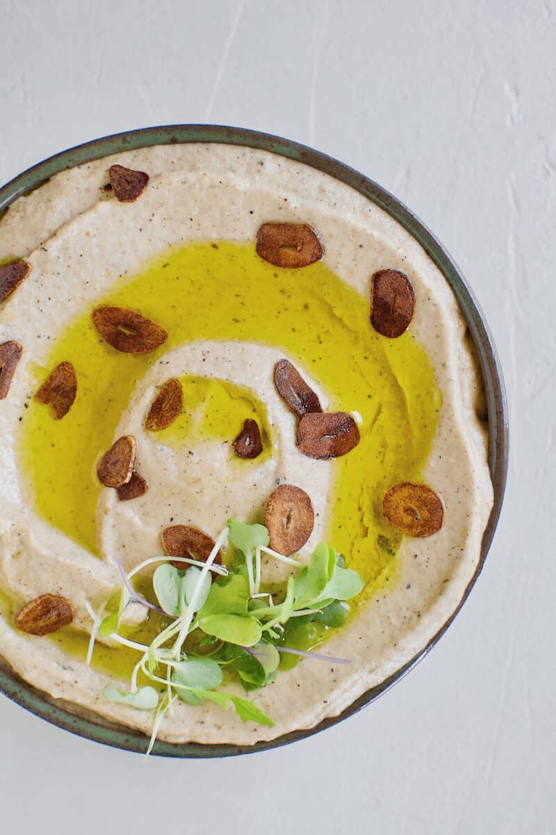 Baba Ghanoush with Toasted Garlic in a bowl, topped with olive oil and sliced toasted garlic.