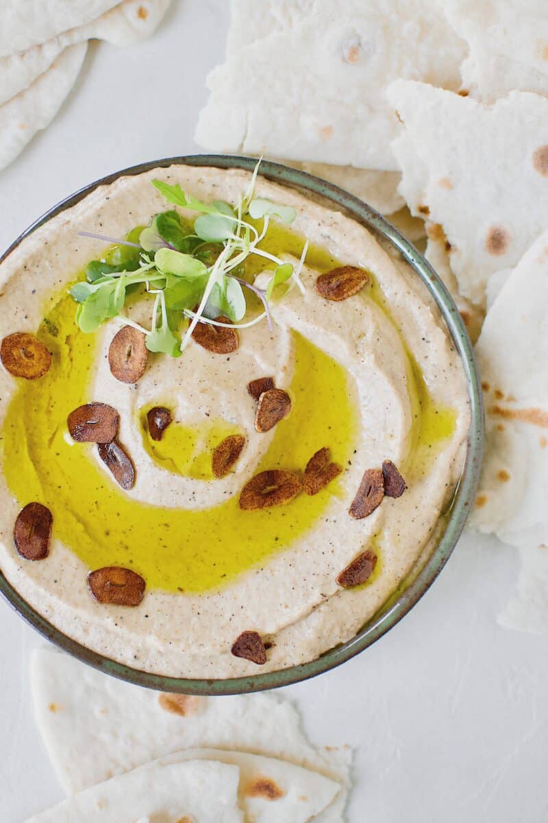 Baba Ghanoush with Toasted Garlic in a bowl, topped with olive oil and sliced toasted garlic.