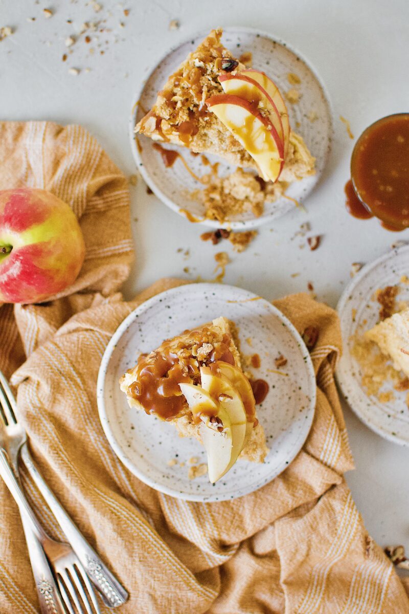 Caramel Apple Crisp Cheesecake topped with caramel sauce and sliced apples.