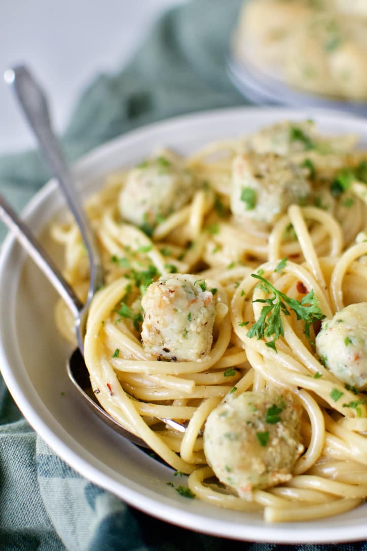 Shrimp Balls served in a white bowl over cooked bucatini pasta.