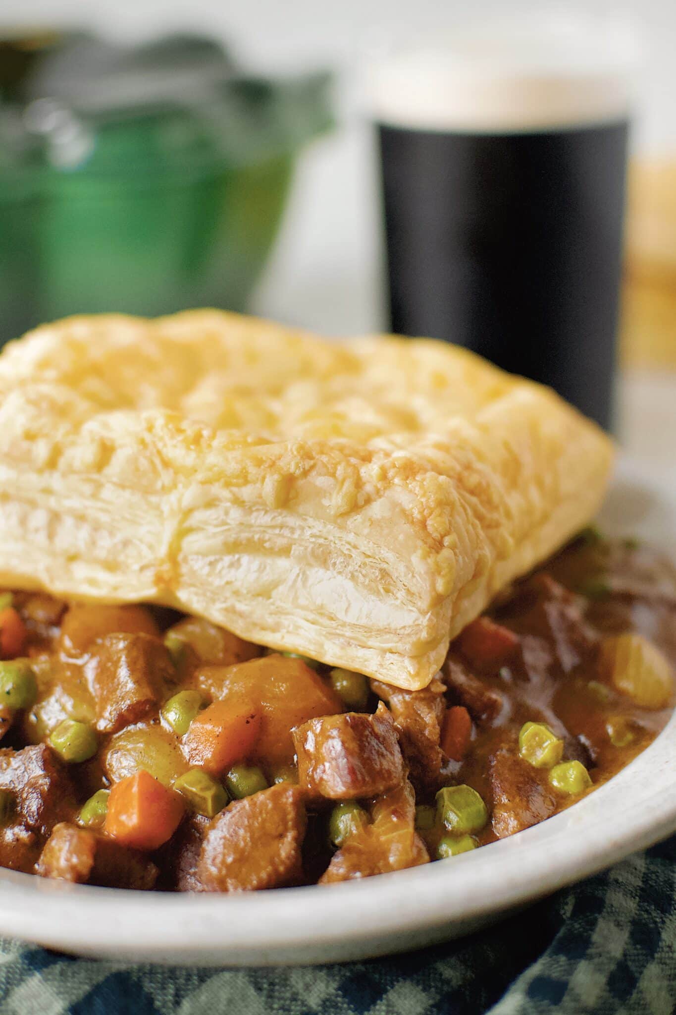 Beef Pot Pie topped with an Irish Cheddar Puff Pastry Square, ready to eat with a Guinness in the background.