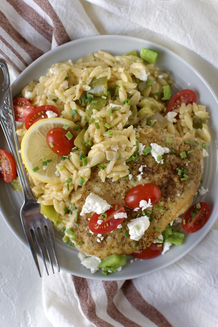 Lemon Orzo Chicken with Feta and Tomatoes finished and ready to eat, on a plate.