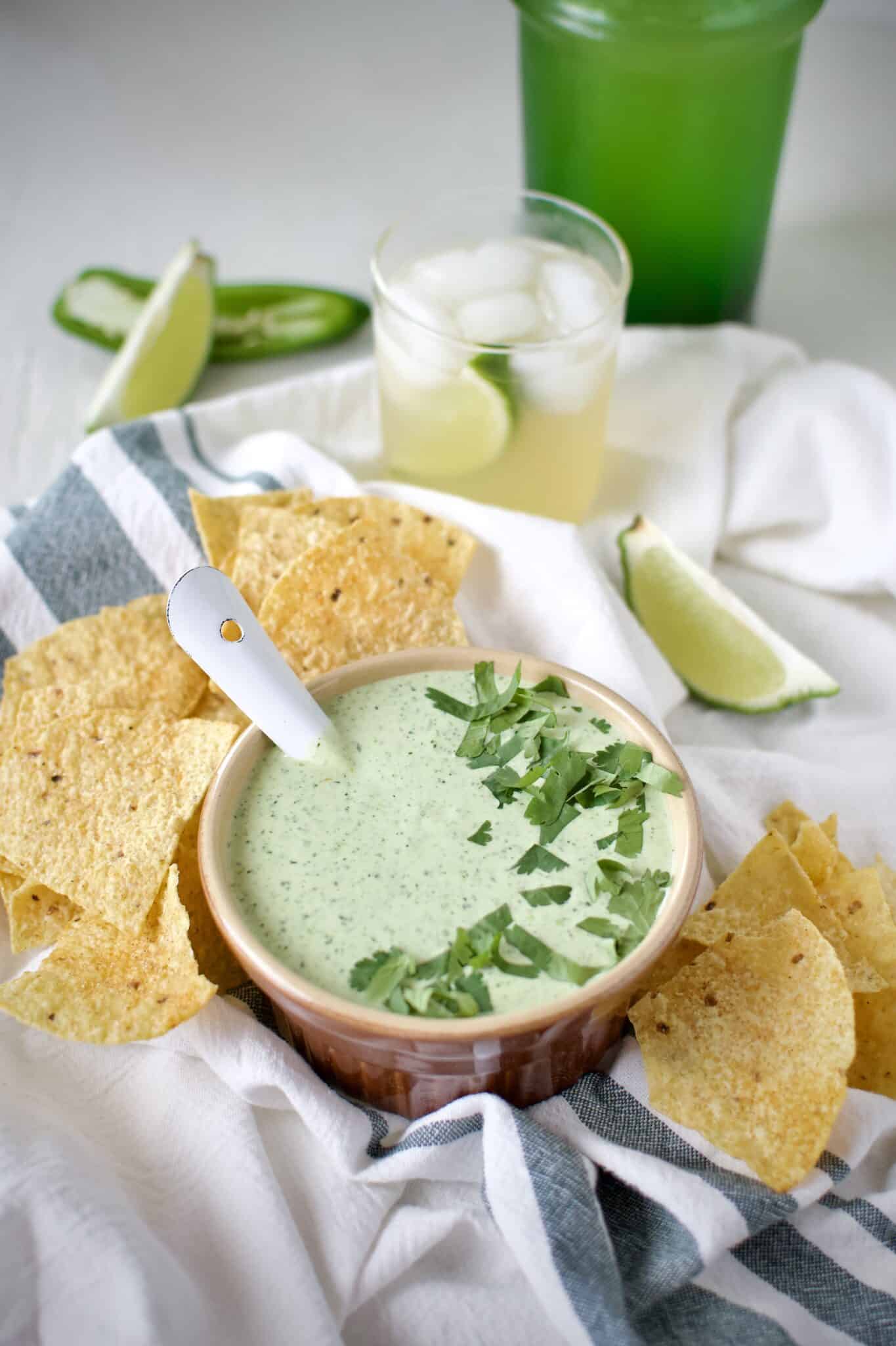 Creamy Jalapeño Dip served with chips and alongside a fresh margarita.