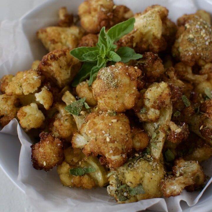 Fried Cauliflower in Olive Oil in a bowl ready to eat. Garnished with Greek seasoning and oregano.