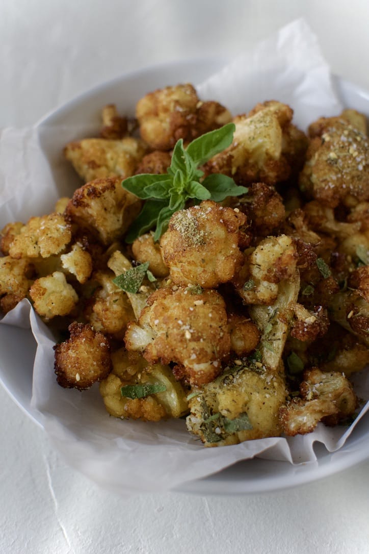 Fried Cauliflower in Olive Oil in a bowl ready to eat. Garnished with Greek seasoning and oregano.