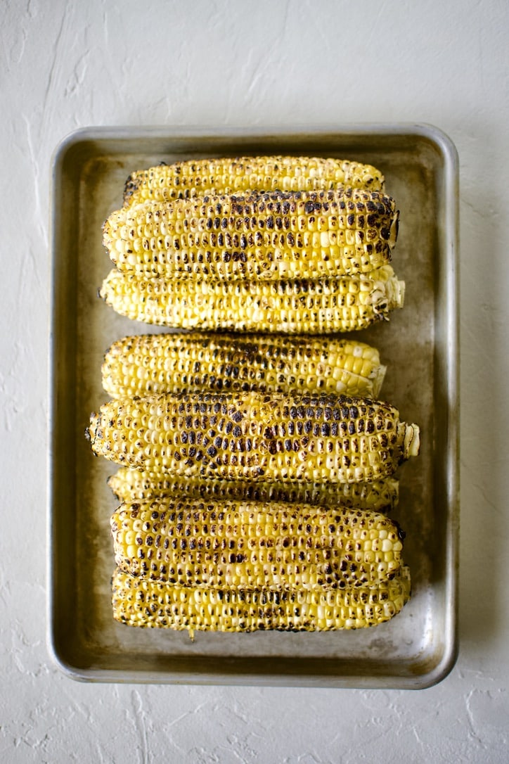 Charred sweet corn on a sheet pan.