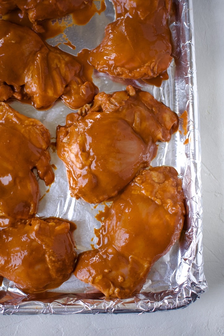 Marinated Chicken thighs on a foil lined sheet pan just before cooking.